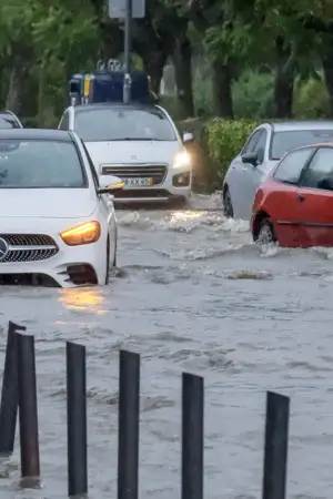 Carros submersos em rua inundada.